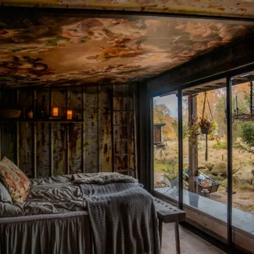 The bedroom at Gullis Gård with a tin roof and panoramic window looking out to the farm