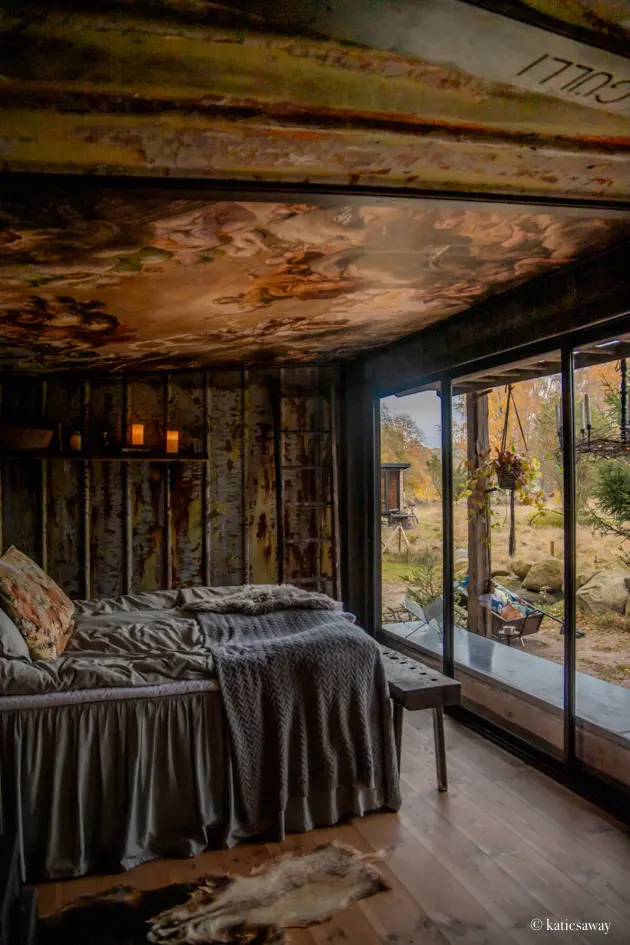 The bedroom at Gullis Gård with a tin roof and panoramic window looking out to the farm