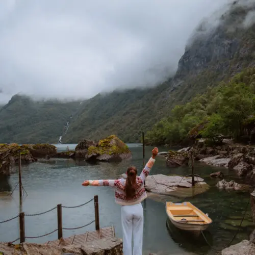 A person standing by Bondhusvatnet lake with a yellow row boat and view of the glacier